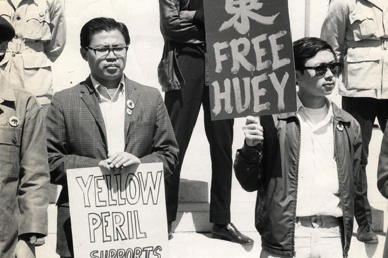 two Asian american men picketing with signs that read free huey